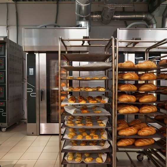 Racks of fresh loaves of bread and buns from ovens in Bakery